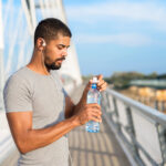 guy on a bridge with bottled water